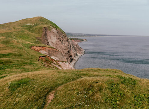 vue sur une falaise de roche grise au bord de la mer avec du gazon sur les terres en &eacute;t&eacute;