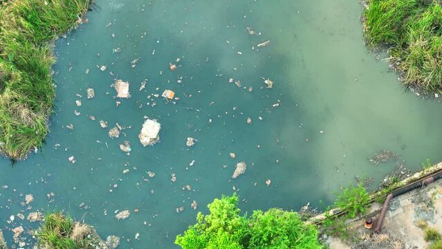 Dirty factory water dumped into rivers hurts fish and plants, messing up nature big time. Chemical Contaminants and sewage pollution concept. Bird's eye view by drone. Stock footage.
