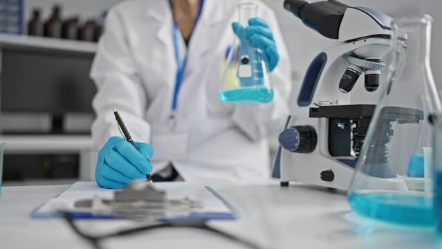 Intriguing glance at the seasoned hands of a senior woman scientist meticulously taking notes in the lab, engrossed in her remarkable test tube experiment
