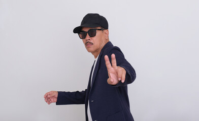 Side view: A man wearing a dark blazer, a hat and sunglasses gave a peace sign with his fingers