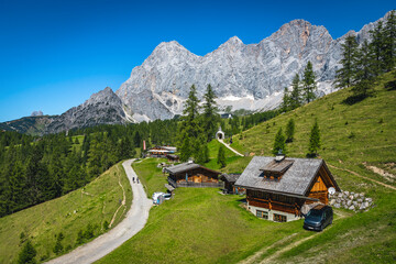 Alpine chalets on the green slopes, Ramsau am Dachstein, Austria - 704253106