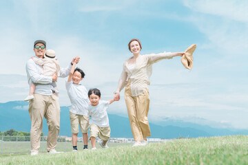 家族旅行・春・夏に青空の見える公園で遊ぶ家族・ファミリー・親子
