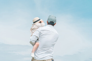Obraz na płótnie Canvas 青空の見える公園で遊ぶパパと娘・親子の後ろ姿 