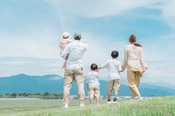家族旅行・青空の見える公園で遊ぶ家族・ファミリー・親子の後ろ姿
