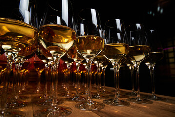 glasses with white wine on the table on black background ready for event 