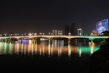 Fototapeta na wymiar Nanning city,Guangxi province, China at night. Bridge over Yong River with colorful reflection