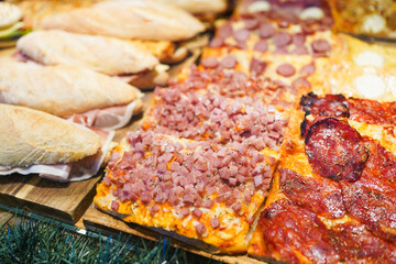 Assorted pizza slices with various toppings on display.