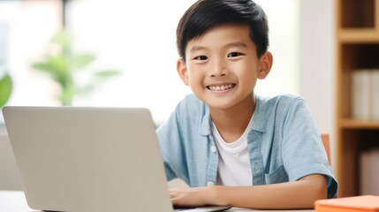  a young boy sitting at a desk with a laptop in front of him and a bookcase in the background.