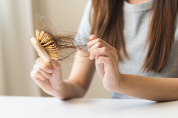Close-up young woman brushing her hair and have many hair loss on the comb