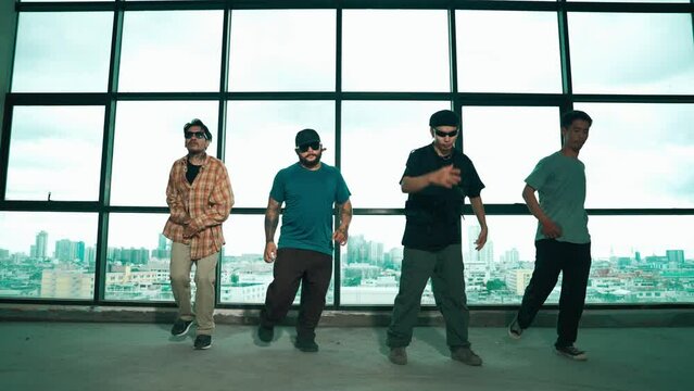 Group of multicultural dancer dancing together with skyscraper. Portrait of multicultural hipster team moving foot step with confident near window with urban city view. Outdoor sport 2024. hiphop.