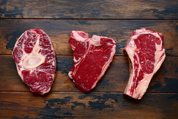Raw organic marbled beef steaks : ossobuko, rib eye ( cowboy ) , T - bone . Top view with copy space.