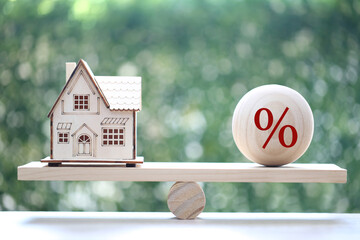 Interest rate up and Banking concept, Model house with Percentage symbol icon on wood scale seesaw on natural green background, Fixed Rate