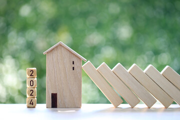 Real estate, 2024 block with model house and falling blocks on natural green background, investment and business concept