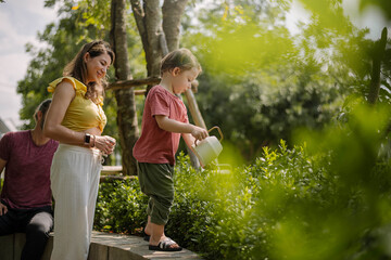 CCaucasian family with little kids son planting and taking care plants together in house backyard...