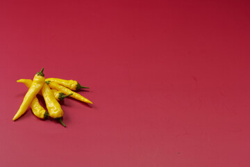 黄色系唐辛子を複数左下に複数配置した赤色系背景あり俯瞰撮影