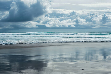 Fototapeta premium The endless dance between sky and sea as wind waves crash onto the shore, sweeping over mudflats and shoals, creating a stunning landscape of clouds and sand