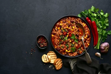 Fotobehang Chili con carne - traditional mexican minced meat and vegetables stew in tomato sauce in a cast iron pan . Top view with copy space. © lilechka75