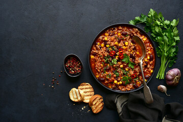 Chili con carne - traditional mexican minced meat and vegetables stew in tomato sauce in a cast iron pan . Top view with copy space. - obrazy, fototapety, plakaty