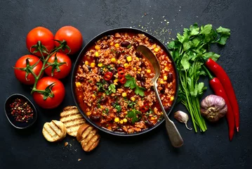 Fotobehang Chili con carne - traditional mexican minced meat and vegetables stew in tomato sauce in a cast iron pan . Top view with copy space. © lilechka75