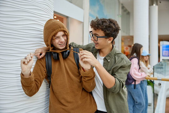 Two funny teen boys fooling around having good time in shopping mall