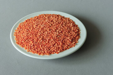 A pile of split red lentils on a white plate