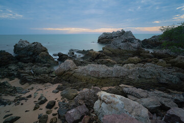 Fototapeta na wymiar Sunrise/sunset at sea, calm waves and rocky shore.
