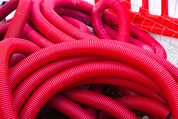 Plastic flexible corrugated pipes of red color twisted into a roll.