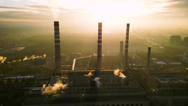 High angle drone footage of thermal power plant chinmeys polluting the atmosphere. Smoke rising from industrial smokestack. Electricity production with fossil fuels concept.
