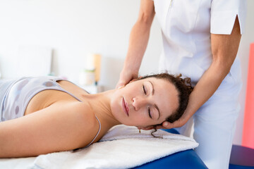 Fototapeta na wymiar Relaxed woman getting neck treatment in osteopathy clinic