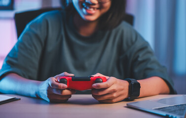 Young asian woman enjoy playing video game by talking on headphones in living room at night.