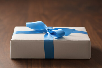 White paper gift box with blue ribbon on walnut wood table with copy space