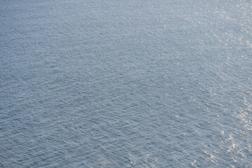 Aerial shot of blue sea surface with sun flare