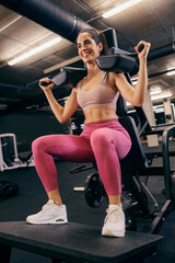 Fototapeta na wymiar A happy sportswoman is doing workouts on standing calf machine in a gym.