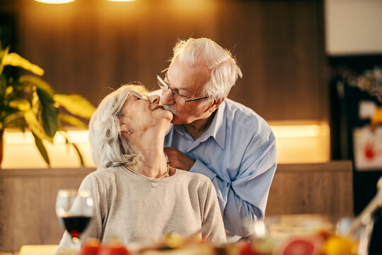 A Senior Couple Is Kissing On Anniversary. A Senior Man Is Putting A Necklace On His Wife.