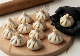 making khinkali for his family close-up. Unrecognizable cook preparing georgian traditional meal of dough and meat at kitchen. National cuisine, cooking process concept.frozen