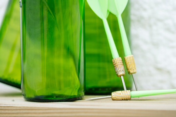 Green darts from a dartboard resting on beer bottles.