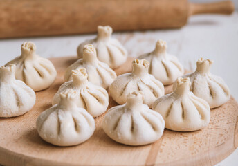 Raw frozen khinkali  on wooden table. Process preparation georgian meal. food concept.