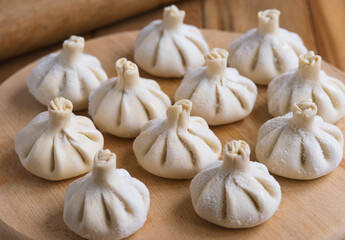 Raw frozen khinkali  on wooden table. Process preparation georgian meal. food concept.