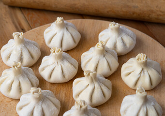 Raw frozen khinkali  on wooden table. Process preparation georgian meal. food concept.