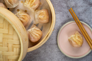 Homemade dumplings dim sum close-up in a bamboo steamer box on table. Horizontal top view from above