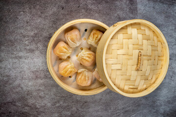 Homemade dumplings dim sum close-up in a bamboo steamer box on table. Horizontal top view from above