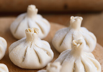 Raw frozen khinkali  on wooden table. Process preparation georgian meal. food concept.