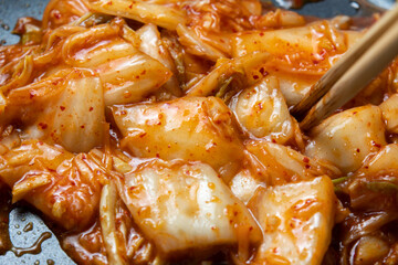 キムチをフライパンで炒める調理シーン。
