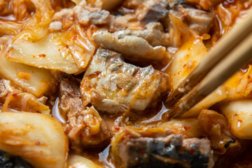 キムチと鯖水煮をフライパンで炒める調理シーン。

