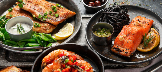 Grilled salmon fish fillet with lemon and strimps. Sea food dishes assorty. Healthy concept
