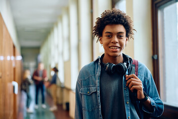 Happy black high school student in hallway looking at camera.