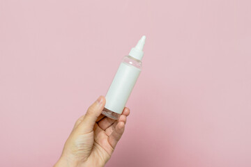 Woman hand holding cosmetic bottle. Cosmetic product branding mockup. Daily skincare and body care routine.