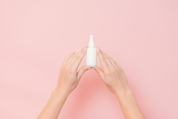 Hand holding glass cosmetic bottle for serum (hyaluronic acid and collagen) on pink background....