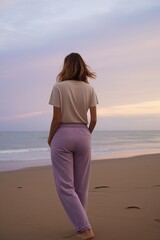 portrait of beautiful young woman with long hair wearing purple crochet beach dress, standing pose walking away from the camera. ocean beach background