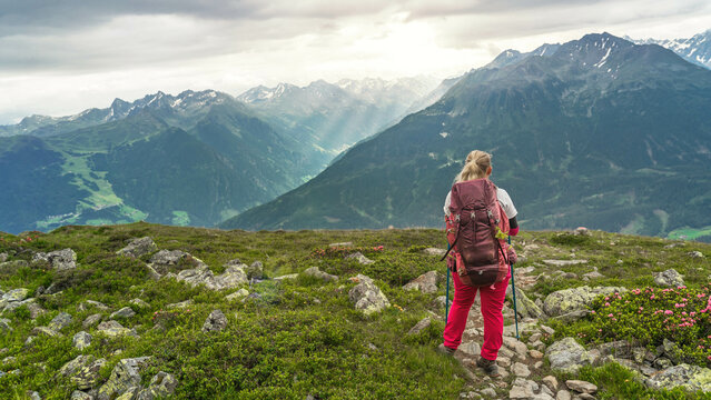 Ein Wanderin mit Rucksack auf der Alpen&uuml;berquerung blickt vom Venet ins Pitztal.